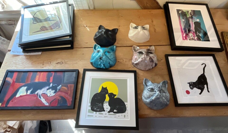 Noe av kunsten som allerede har ankommet til utstillingen. Kattehoder i keramikk av Ingrid Cimmerbeck, maleri av , og mange trykk av Randi Antonsen. Flere bilder med katter, og kattehoder i keramikk på et bord.