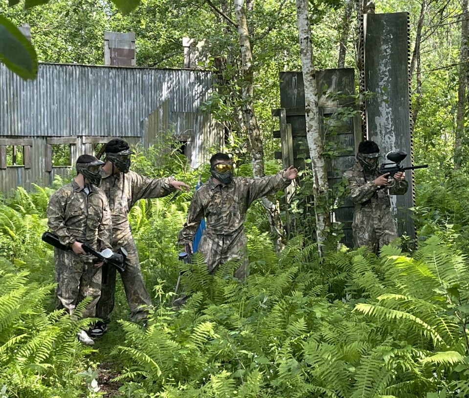 Å jobbe sammen som et team skaper lagånd 4 menn i skogen i kamuflasjeklær.