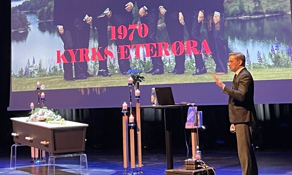 Tor Håkon Gabriel Håvardsen takket Bertelsen gravferd for tilliten og fortalte litt om deres historie også. En mann på scena. Rundt han er det satt opp som en begravelse. Skjerm med bilde av Bertelsen gravferd på