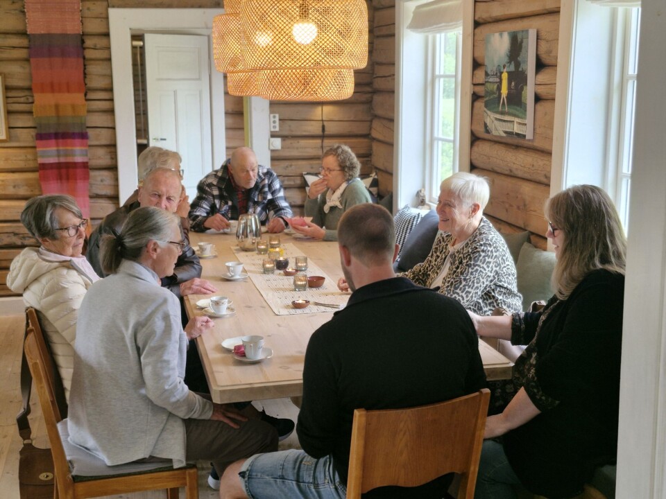 Triveleg med sprett-opp-kafé med langbord og livleg samtale Folk rundt bord i ei fin tømmerstue