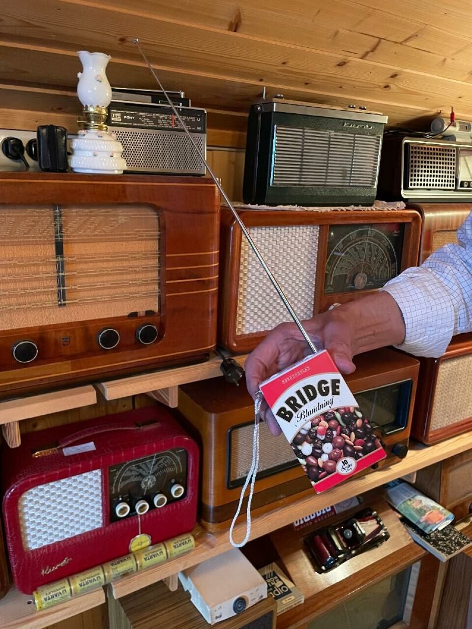 En av radioene i samlingen på garasjeloftet. Radioer. En hånd som holder en radio det står 'Brigde Blanding' på.