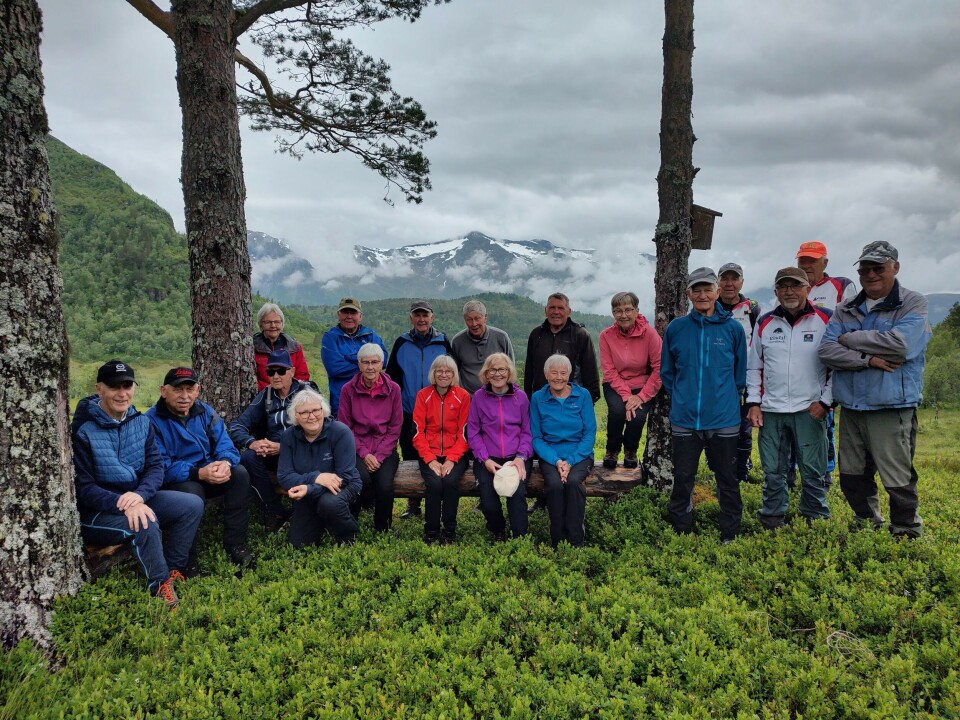 En pause på seterstølen. Ei gruppe turkledde folk oppstilt til fotografering i marka.