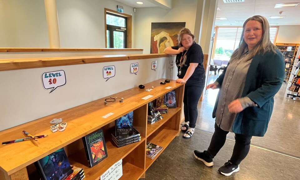 Ida og Gunhild ved 'premiebordet' på Rindal folkebibliotek. To damer ved en reol i et bibliotek.