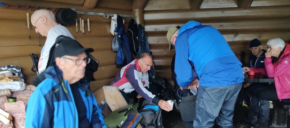 Einar serverer nykokt kaffe. Flere turkledde folk i en gapahuk.