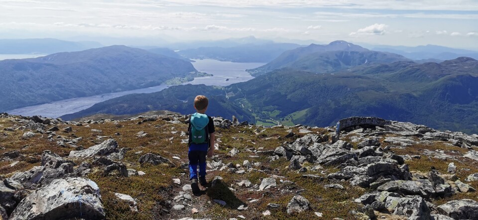 Førskolebarna på tur til Hjelmen En liten gutt med sekk på ryggen på en fjelltopp.
