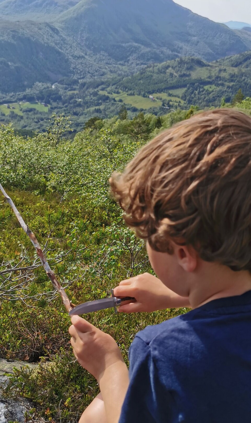 Førskolebarna på tur til Hjelmen En liten gutt som spikker med kniv på en kvist.