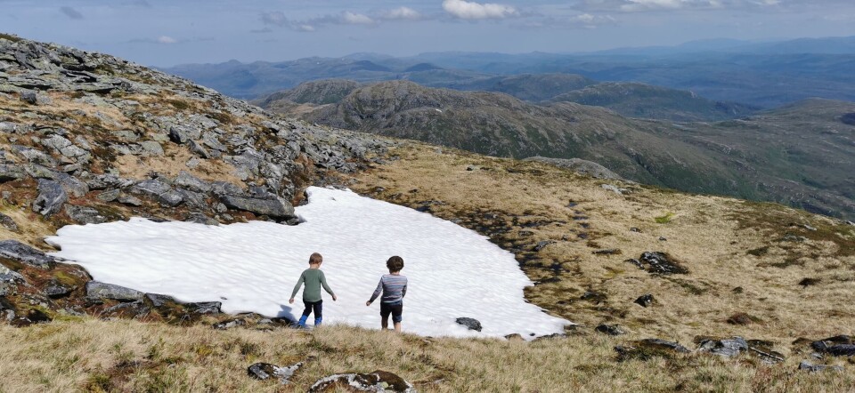 Førskolebarna på tur til Hjelmen To små gutter ved en liten snøskavl på et fjell.