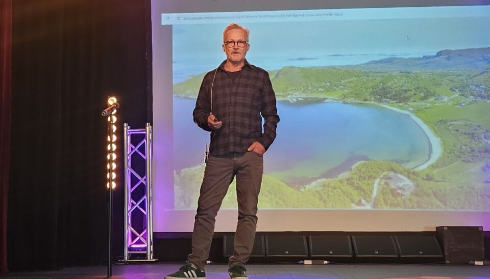 Roar Svenning viser hvordan deler av Stokkøya ser ut. Midt i bildet er hans hjemsted en mann står på en scene og ser ut over salen. Bak han er det en powerpoint med bilde av natur, havet og strand