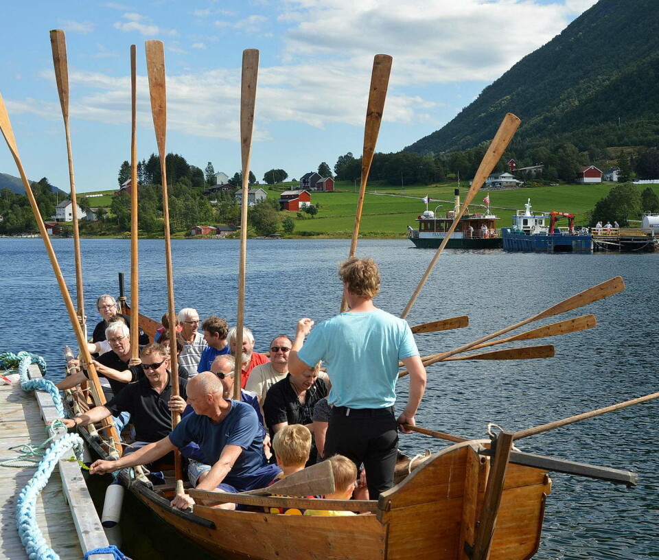 I 2009 fekk historielaget bygd den klassiske kyrkjebåten «Hjelmkonnå». Her klar til tur ein såkalla Fjorddag – med sundbåten «Framnæs» i bakgrunnen. En robåt med mange folk ombord, og flere årepar.