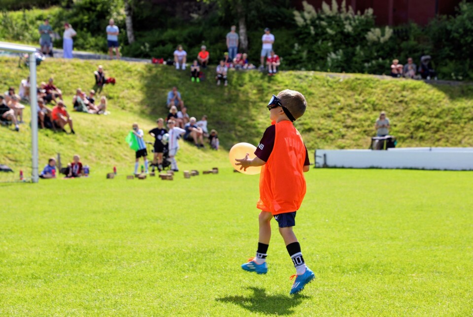 Gutt på banen holder ballong og går mot mål på sidelinja.