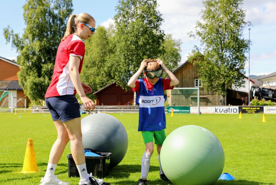 Gutt står på banen mellom to store baller og tar på seg stor briller som ser ut som slalombriller.