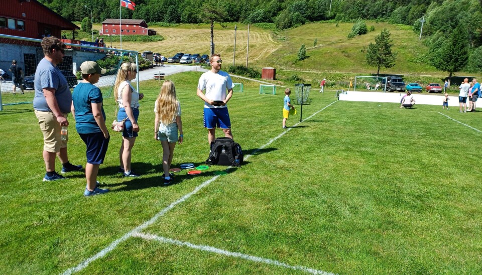 Instruktør Lars Settemsdal tar imot folk som vil prøve frisbeegolf. Flere personer ved en fotballbane.