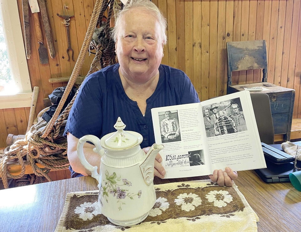 – Denne fine kaffekanna fekk mor Ingrid av Guro Grøtan, seier Marta Havdal – som forærer kanna vidare til Bøfjorden Historielag. Ei smilende godt voksen dame som holder fram et hefte med skrift og bilder. Foran henne på bordet står ei kaffekanne av porselen.