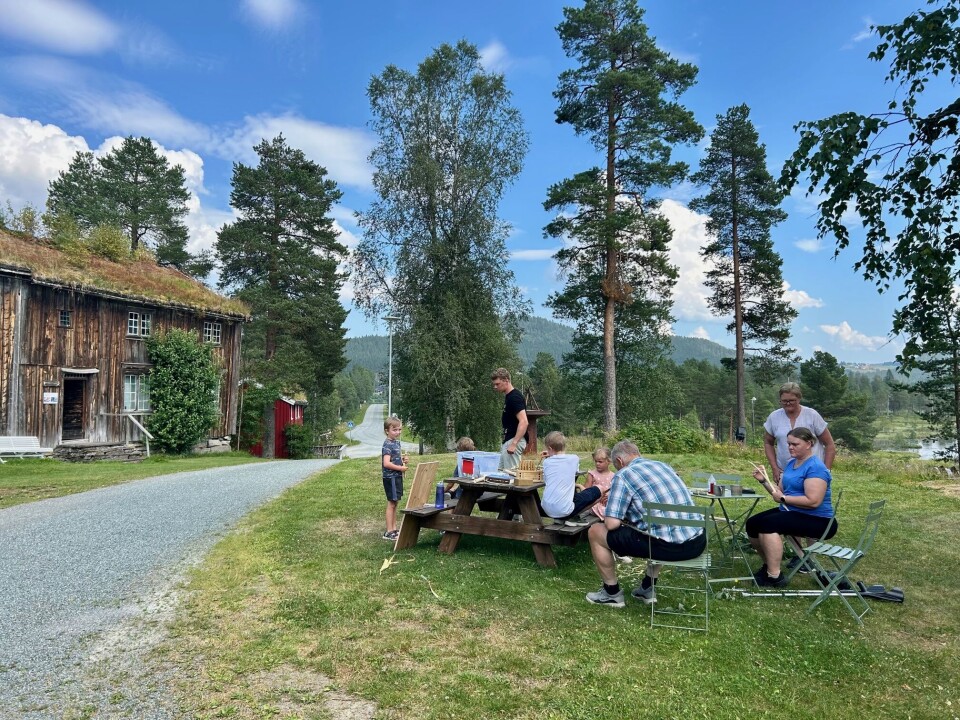 Hyggelige omgivelser på Rindal skimuseum Folk på benk ute i tunet med gamle hus