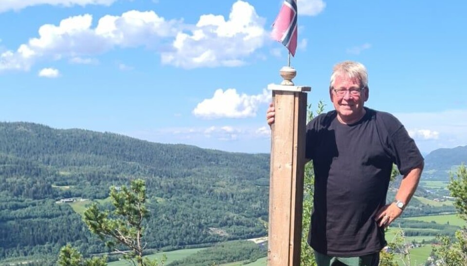 Svein Otto Nilsen. mann ved benk med flagg på fjelltopp