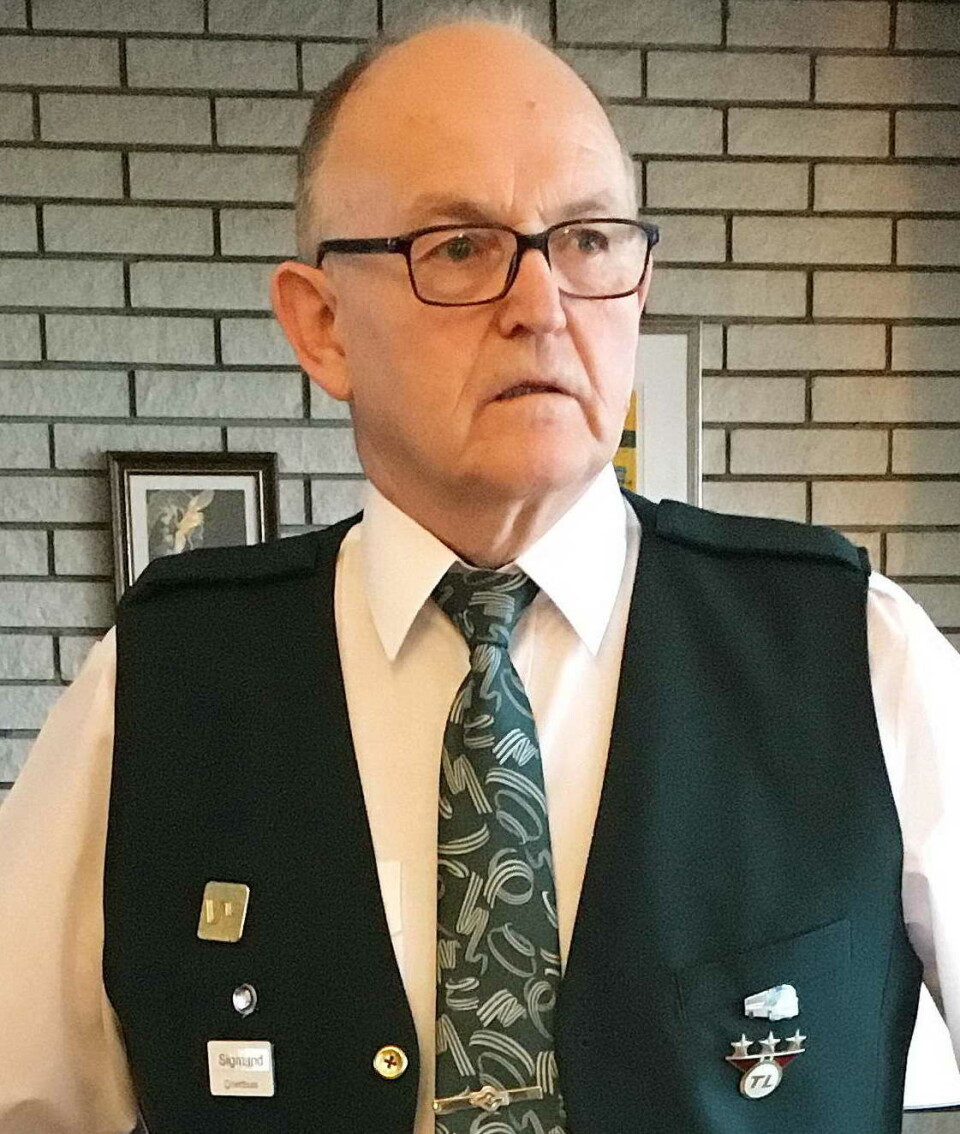 Han som har styringa på museet søndag: Sigmund Gravvold. Mann med hvit skjorte, grønt mønstret slops og blå vest med noen merker på. Mannen har lite hår og briller og ser alvorlig ut.