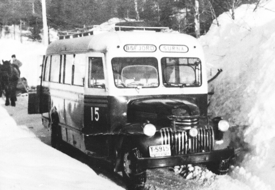 Vintervegen stoppa ved Elverhøy i Bøverdalen. Frå øvst i bygda måtte hesten dra lass og folk. Buss på sort/hvitt bilde. Nummerert med nr 15 med høye snøskavler rundt og dårlig brøyta vei. Hest og slede i bakgrunnen.