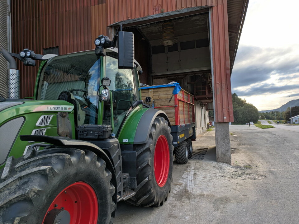 Lars Holte fra Øye er en av kornbøndene som har levert korn til mølla denne uka. Grønn, stor traktor med henger rygger inn i port med henger full av korn