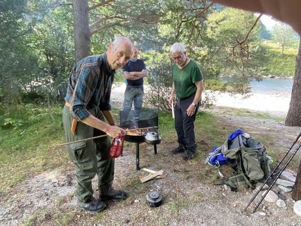Stavgangtur langs Toåa Tre gråhårede menn rundt ei bålpanne i sommervær. Den ene holder en svartkjel på ei stang.