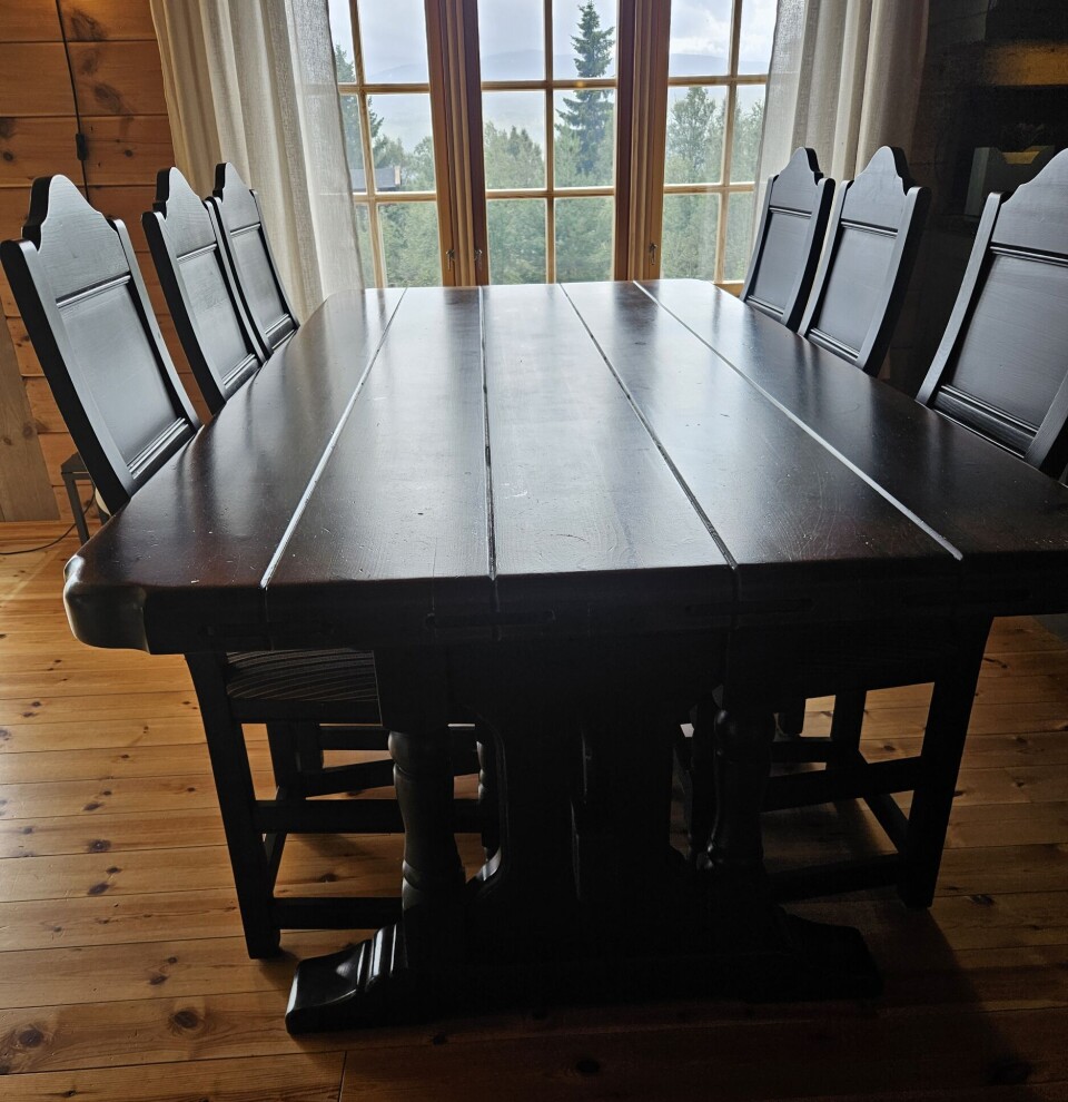 Spisebord til salgs Et mørkt grovt spisebord av tre, med seks stoler.