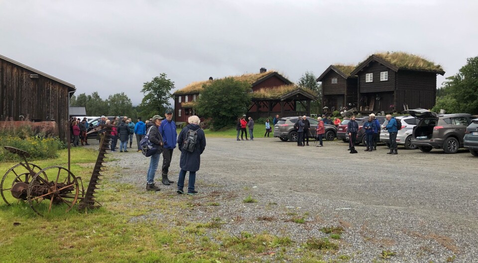 Nestu Røen. Mange turkledde mennesker på et stort gårdstun, i grått og vått sommervær.