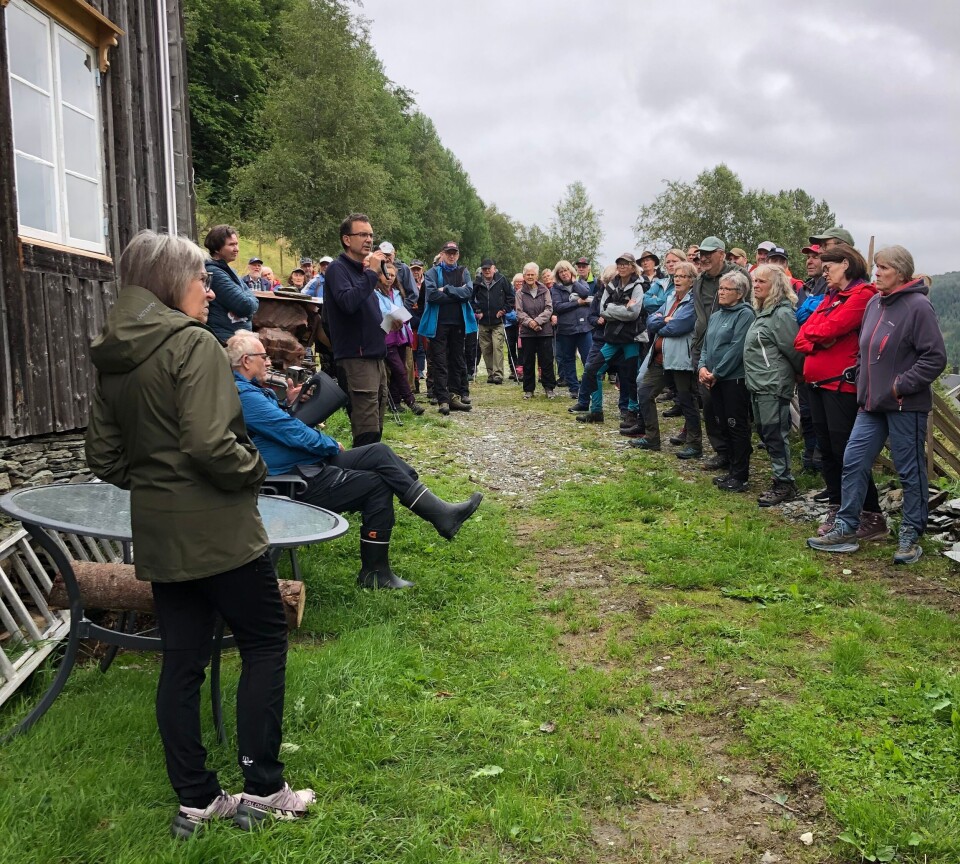 Kolbjørn Nerland orienterer om restaureringa. Mange turkledde mennesker samlet foran et gammelt hus, de