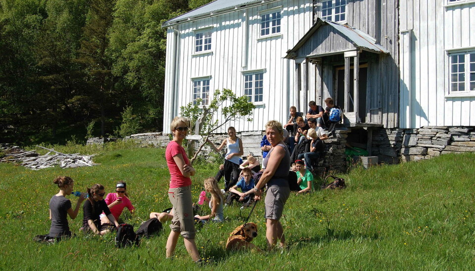 Trodalen er ynda turmål. Her skuletur for nokre år sia. Ei gruppe med barn og voksne foran en stor gammel hvitmalt gårdsbygning i tre. Sol og sommer.