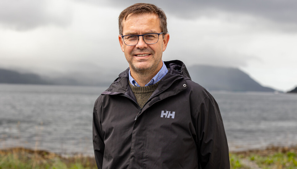 Jakob Nørbech, daglig leder i Surnadal, Heim og Tingvoll Gjensidig Brannkasse. Portrettbilde av en voksen mann med mørkt hår og briller, kledd i allværsjakke. Fjord og fjell og tåke i bakgrunnen.