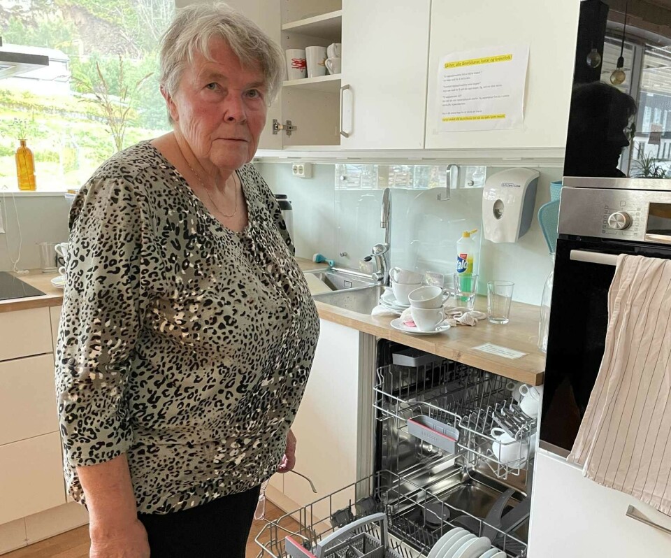 Wenche Kvendset i sving med å ordne opp etter arrangementet. Ei dame med kort grått hår som står foran ei oppvaskmaskin på et kjøkken.