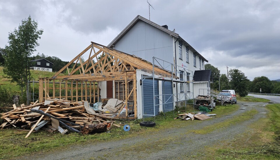 Den gamle garasjen ved Røde Kors huset rives Stort hvitt hus med Røde Kors logo med en garasje ved siden av som er delvis revet