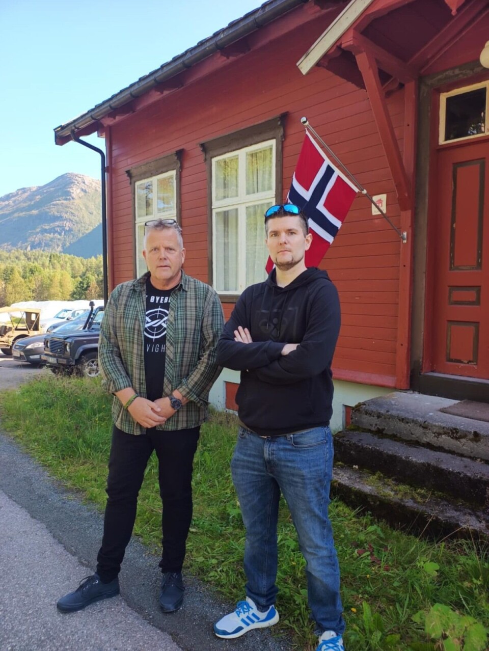 Jo Inge Øverland og Petter Forberg er primus motorar for den forsvarshistoriske samlinga på Åsen. To menn, en i grårutete skjorte og en med blå hettegenser utenfor et rødt hus med norsk balkongflagg. Begge med solbriller på hodet. Biler til venstre på bildet.
