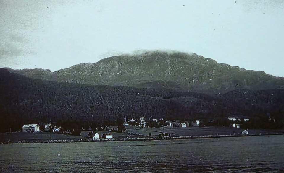 På ekra på garden Indre Rød i Halsa naudlanda den eine av dei to Messerschmittane. Svart hvitt bilde av gårde ved fjorden med en stor åker foran.