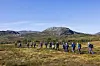Mange mennesker som går på tur. Fjell i bakgrunnen.