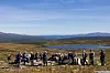 Mange mennesker med ei tjønn og fjell i bakgrunnen.