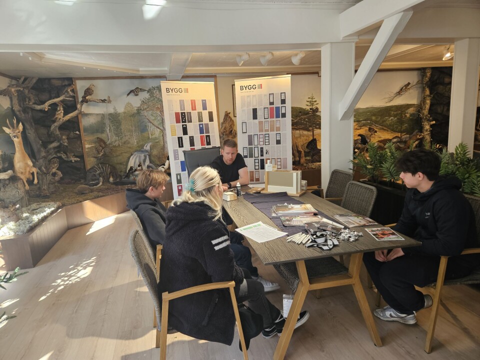 Fra Bygg sin stand i andre etasje. Elever sitter ved et bord og lytter på mann orienterer