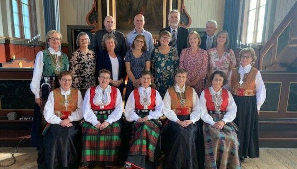 Alle som var konfirmert i Rindal kyrkje i 1975 var invitert til gudsteneste og samling på Menighetshuset siste sundagen i august. Etter lyden å dømme, var det mangt dei hadde å snakke om. Takk til alle som kom, og takk til soknerådet som inviterer og steller i stand. Rosene i framgrunnen er til minne om dei to som har gått bort sidan konfirmasjonstida. oppstilt bilde i kirke av eldre pent kledd i bunad, kjole og dress