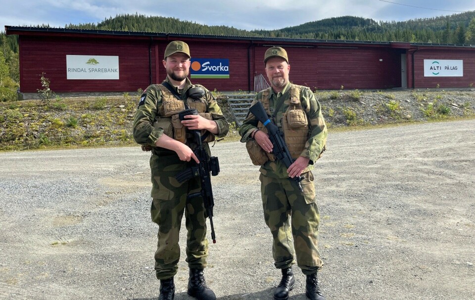 Områdetillitsvalgt Sivert Sættem og liaisonoffiser John Arnolf Merkenes synes at Stampmyra er en godt egnet plass for HV-øvelse. To smilende menn i militæruniform på en grusplass foran et lavt trebygg. Sol og sommer.