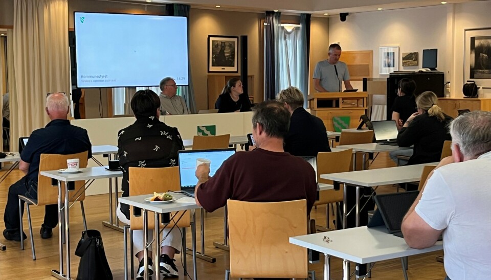 Slit framleis med meirforbruk Flere personer som sitter ved små bord i et møterom.