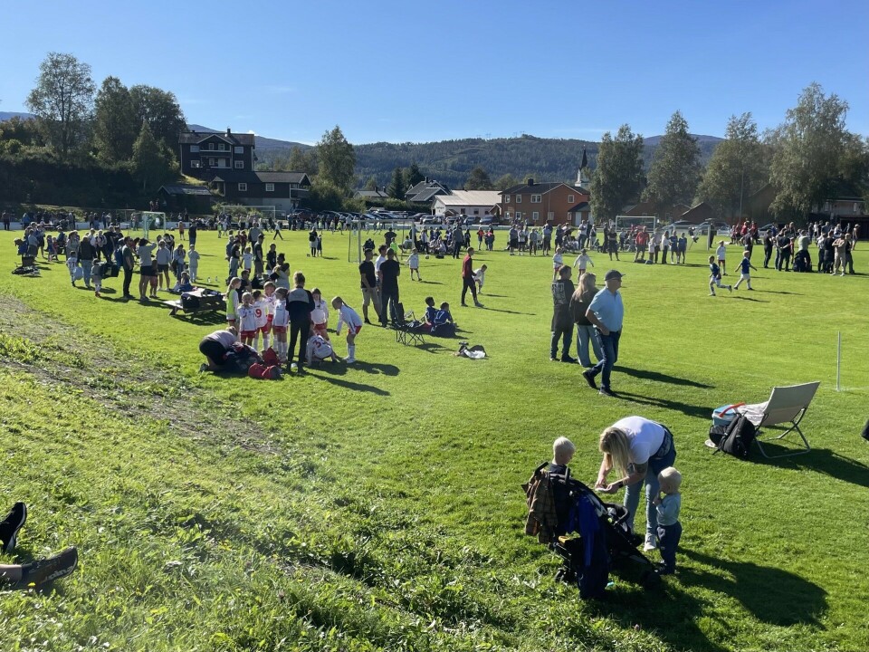 Rindalscup i strålende vær Oversiksbilde over plassen. Ser barn som spiller fotball og mennesker som står å kikker på.