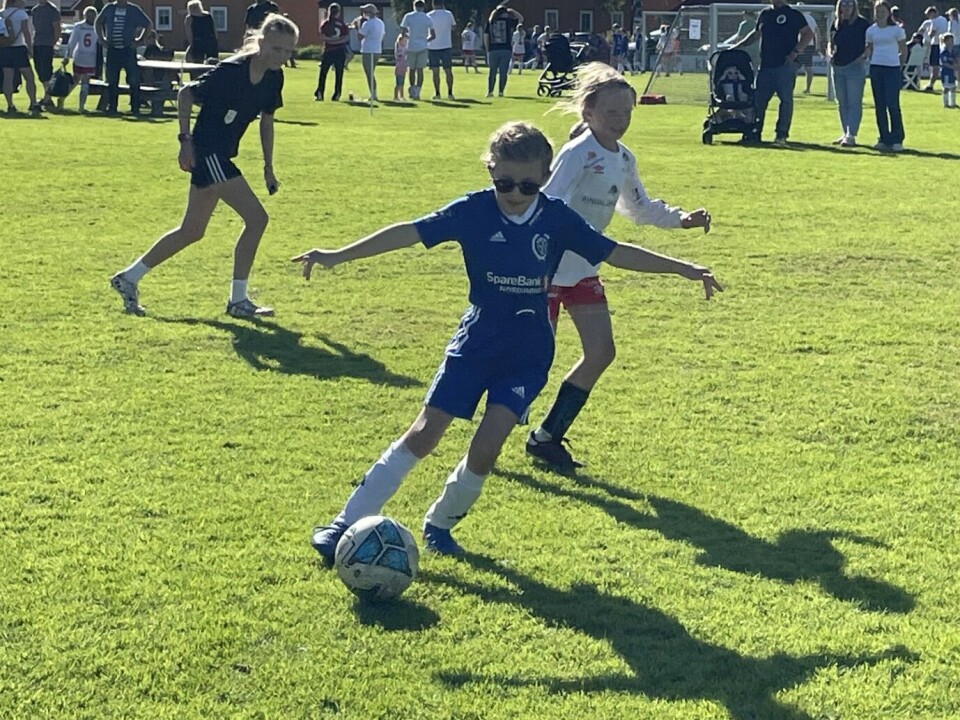 Rindalscup i strålende vær En jente i blå drakt som kjemper om å så ballen forbi motstanderen i hvit.