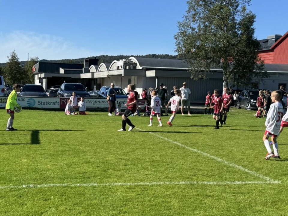 Rindalscup i strålende vær Rindal i hvite drakter spiller mot mørk rød. Keeper i gul drakt som spiller for Rindal står med ballen i hendene, klar til å spille den ut igjen.