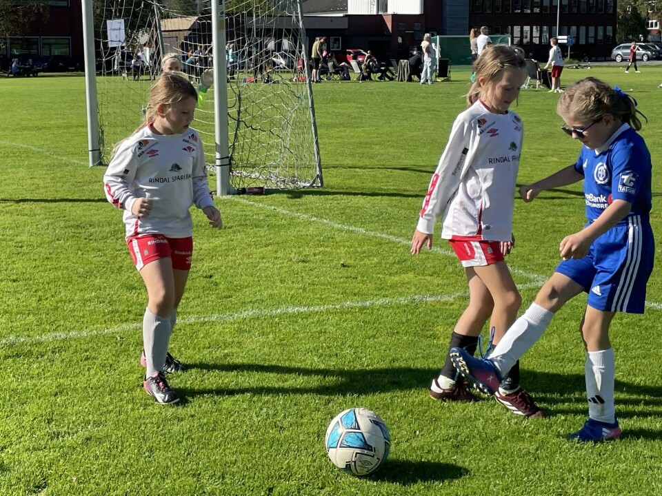 Rindalscup i strålende vær To jenter med hvite drakter fra rindal mot en jente i blå fra Surnadal kjemper om ballen.