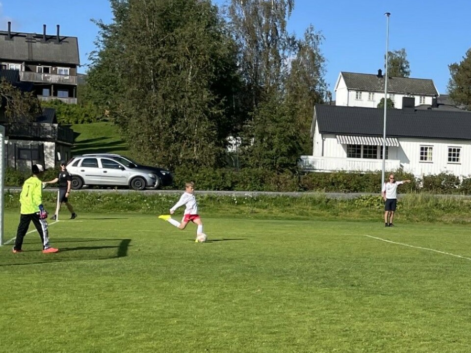 Rindalscup i strålende vær En gutt fra Rindal i hvit tar i fart for å skyte ballen fremover. Her spiller Rindal mot Surnadal i blå drakter.