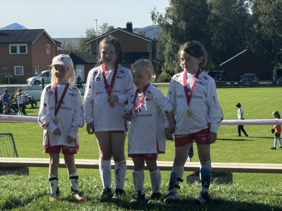 Rindalscup i strålende vær Fire jenter i hvite og røde drakter som står oppstilt med medalje rundt halsen.