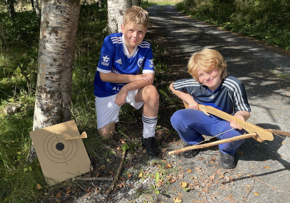 Einar Vetleseter Melling og Lars Isak Petersen fekk skyte med «hardbust». Her ein imponerande åttar! To gutter i blå t-skjorter sitter på huk med en armbrøst. En blink med pil i står lent mot et tre ved sida av.