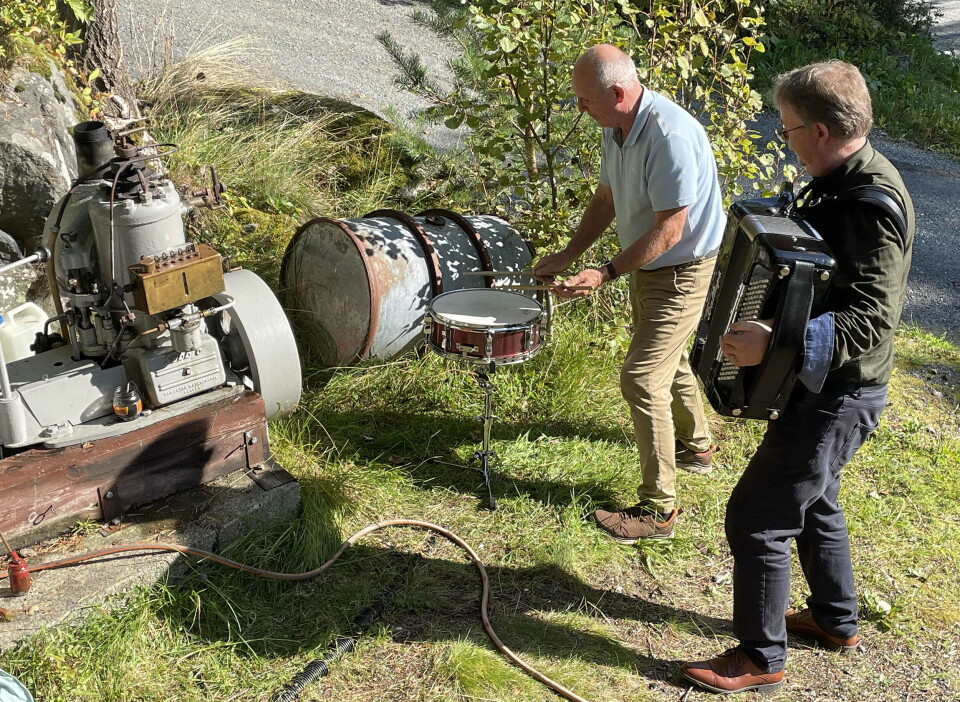 Tony Hopen og Peder Hønsvik musiserer - med Sabben som rytmehaldar. To menn står ute. En med trekkspill, og den andre spiller tromme. En båtmotor står ved siden av.