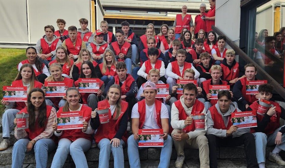 Surnadalsrussen stiller opp i år også, men i Rindal mangler det likevel en del bøssebærere. Mange unge (vgs-elever) som sitter i ei trapp. Ei smilene dame med rør t-skjorte står ved siden av.