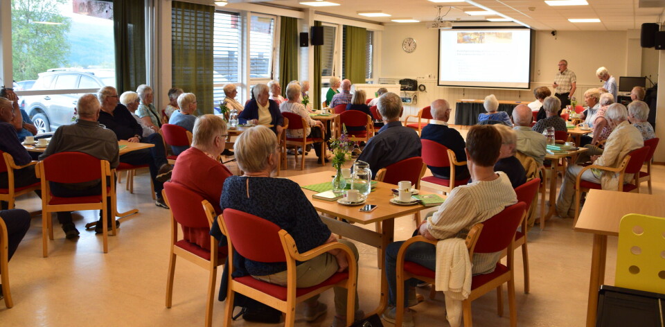 Godt oppmøte på åpen dag, som vanlig. Et forsamlingslokale med flere personer som sitter rundt små bord.