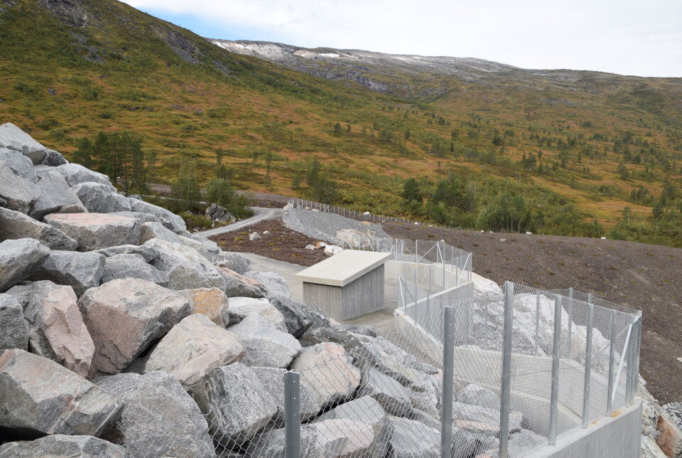 Hele området nedstrøms Gråsjødammen er gjerdet inn permanent, slik at verken for folk eller dyr skal oppholde seg der. Det er naturlig nok ikke trygt å ferdes der vannet slippes ut fra dammen. Landskap etter anleggsarbeid på fjellet. Store steiner som er stablet oppå hverandre. Sommer og blå himmel.