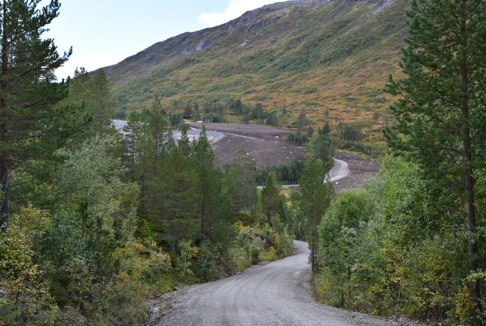 På vei opp mot Gråsjødammen og Gråhaugen kan man nå se at området nå er ryddet, og tilbakeført til naturen. Fjellandskap og en grusvei. Sommer og blå himmel.